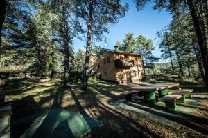una cabaña en el bosque con bancos y árboles en Casa Espinalbet, en Castellar del Riu