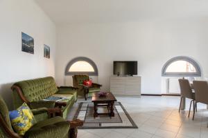 a living room with green couches and a tv at La Casetta in Tremezzo