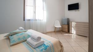 1 dormitorio con 1 cama con toallas y TV en Welcomely - Il Lentischio en Càbras