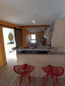 a kitchen with two red stools in front of a counter at Pont de la Chaux 2 in Chaux-des-Crotenay