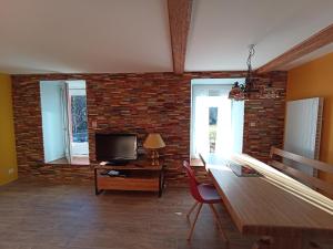 a living room with a tv and a brick wall at Pont de la Chaux 2 in Chaux-des-Crotenay