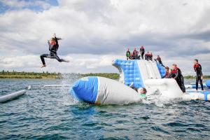 un grupo de personas saltando de una balsa inflable en el agua en Camp David Sport Resort holiday complex on Lake Schladitz, Rackwitz, en Rackwitz