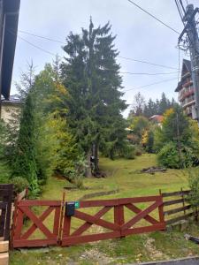 a wooden fence in front of a yard with a tree at Apartament Aosta Central Sinaia in Sinaia