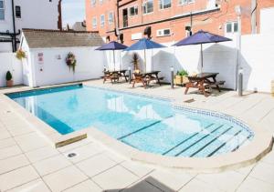 a swimming pool with tables and umbrellas next to a building at Doric Hotel in Blackpool