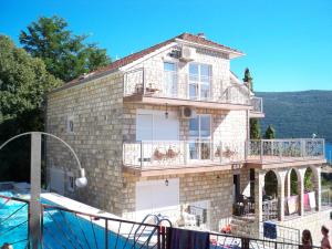 a large brick house with a balcony and a pool at Vila Ćorović in Kumbor