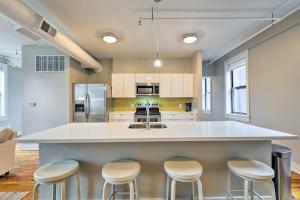 una cucina con ampia isola bianca con sgabelli da bar di Sunny Dtwn Apartment, Walk to Washington Park a Cincinnati