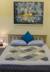 Una cama con una almohada azul y una pintura en la pared en Bliss Beach en Negombo