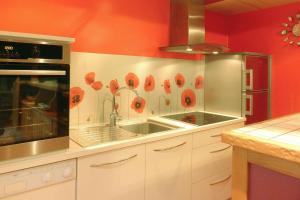 - une cuisine avec des murs rouges, des placards blancs et un évier dans l'établissement Cottage, Buguélès-Penvénan, à Penvénan