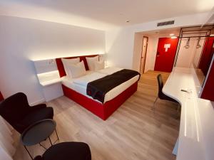 a hotel room with a bed and a desk and chairs at DORMERO Hotel Hof in Hof