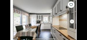 una cucina con tavolo e sedie e una cucina con armadietti bianchi di Livremont7 a Malmedy