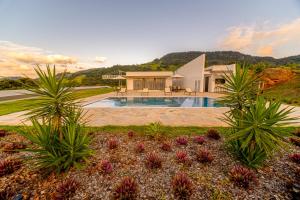 a house with a swimming pool in the middle of a garden at Pousada Boutique Mirante dos Adelphos in Socorro
