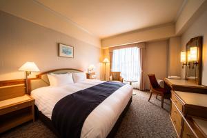 a hotel room with a large bed and a desk at Kure Hankyu Hotel in Kure