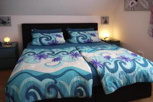 a bedroom with a bed with a blue and white comforter at Apartments, Frankenau in Frankenau