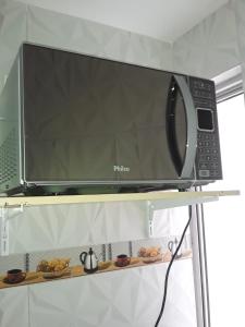 a microwave sitting on top of a shelf at FLAT O POINT do CARNAVAL do FAROL da BARRA in Salvador