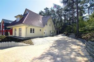 a large white house with a driveway at Doppelhaushälfte Ostseehaus II, Trassenheide in Trassenheide
