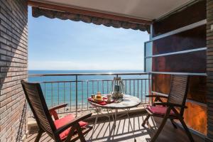 uma varanda com 2 cadeiras e uma mesa com vista para o oceano em Apartamento con vistas al mar primera linea de playa del Postiguet em Alicante