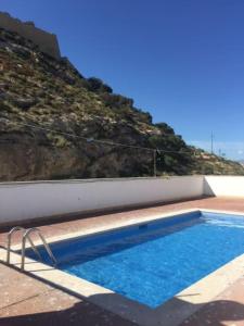 a blue swimming pool with a mountain in the background at Apartamento con vistas al mar primera linea de playa del Postiguet in Alicante