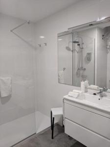 uma casa de banho branca com um chuveiro e um lavatório. em Apartamento con vistas al mar primera linea de playa del Postiguet em Alicante