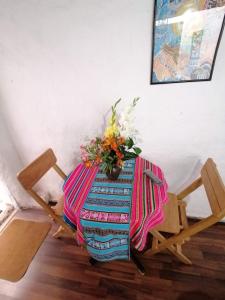 a table with a vase of flowers on top of it at Asiriq Wasi Guest House in Cusco