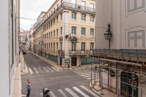 um homem andando por uma rua da cidade com edifícios em Modern 1BDR in Downtown Lisbon by LovelyStay em Lisboa