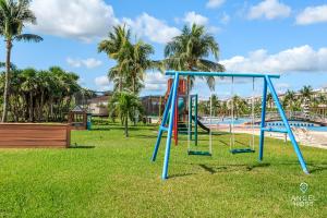 a swing set in a park next to a pool at Luxury Condos at Mareazul Beachfront Complex with Resort-Style Amenities in Playa del Carmen