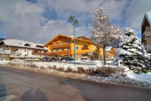 een groot geel gebouw met sneeuw op de grond bij Hotel Serles Superior in Dobbiaco