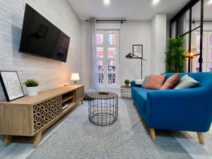 a living room with a blue couch and a tv at Charming Madrid Styles in Madrid