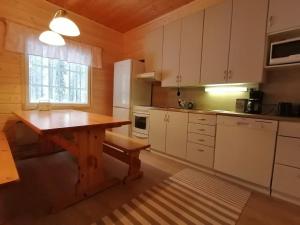 a kitchen with white cabinets and a wooden table at Velhonkieppi in Kittilä