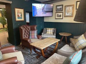 a living room with chairs and a table and a tv at The Bridge Inn in Holmrook