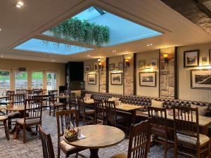 a restaurant with wooden tables and chairs and a skylight at The Bridge Inn in Holmrook