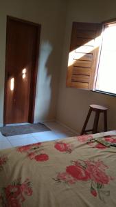 a bedroom with a bed with a floral bedspread at Linda casa com 2 quartos, um com ar e outro com ventilador, e garagem in Parnaíba