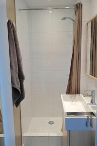 La salle de bains blanche est pourvue d'un lavabo et d'une douche. dans l'établissement Vue Sur Mer, à Port-en-Bessin-Huppain