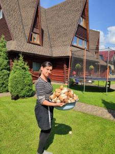 una mujer sosteniendo un plato de comida delante de una casa en Trembita, en Mizhhirya