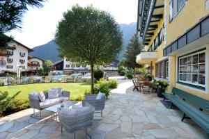 un patio con sillas y mesas en un edificio en Posthotel Mayrhofen, en Mayrhofen