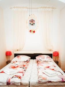 ウィーンにあるヴォーネン イム ヘルツェンフォンウィーンのベッドルーム1室(ピンクのシーツとシャンデリア付)
