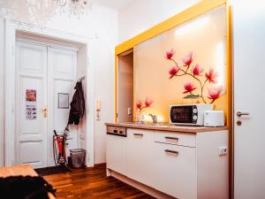 a kitchen with white cabinets and pink flowers on the wall at Wohnen im Herzen von Wien in Vienna