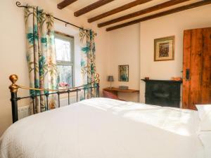 a bedroom with a white bed and a fireplace at 2 Oddfellows Cottages in Hope