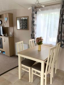 uma mesa de jantar com cadeiras e um vaso de flores em Mollys Retreat pet friendly three bed caravan with small garden Newquay Bay Resort Quieter area of park em Newquay