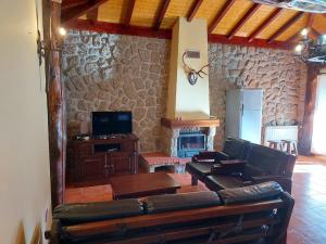 a living room with leather furniture and a stone wall at Casa das Vessadas in Celorico de Basto