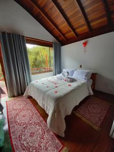 Un dormitorio con una cama grande con ventana. en Pousada Som das Aguas, en Gonçalves 58 fotos más