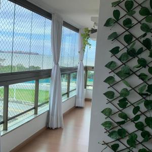 a room with large windows with white curtains at Aconchegante apt com vista para o mar de Camburi in Vitória