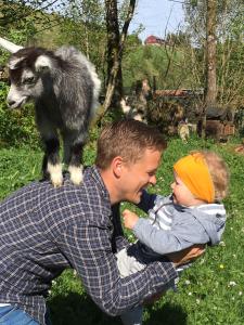 un hombre sosteniendo un bebé con una cabra en sus hombros en Skjerping gårdshus,, en Lonevåg