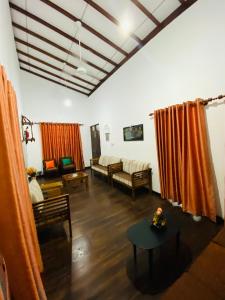 salon z pomarańczowymi zasłonami, kanapą i stołem w obiekcie Uva Escape Holiday Bungalow w mieście Bandarawela