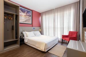 a hotel room with a bed and a red chair at Hilton Garden Inn Praia Brava in Itajaí