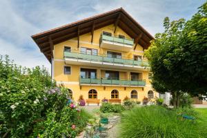 um edifício amarelo com varanda e algumas plantas em Hotel Preishof em Kirchham