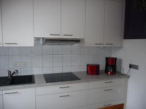 una cocina con armarios blancos y un aparato rojo en Wohnung "Niedersachsen", en Hohenhameln