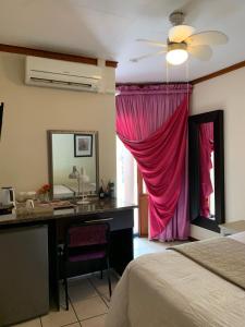 a bedroom with a desk and a pink curtain at Tengo guest house in Phalaborwa