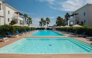 a large swimming pool with chairs and umbrellas at Evasion Corse Direct mer Piscine Terrasse in Moriani Plage