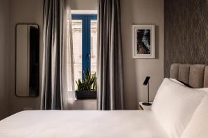um quarto com uma cama branca e uma janela em Amery House em Sliema