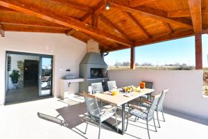 eine Terrasse mit einem Tisch, Stühlen und einem Kamin in der Unterkunft Villa Marušići 2140 in Marušići